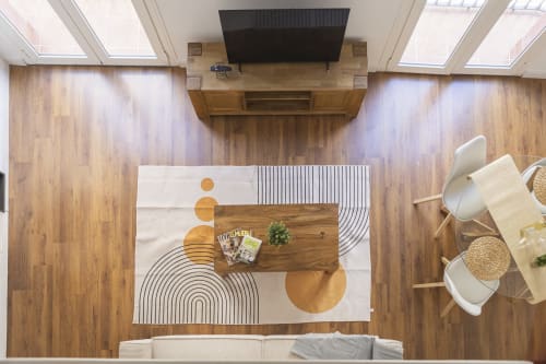 Salón de apartamento moderno en Málaga con suelo de madera, alfombra geométrica, televisor y zona de estar