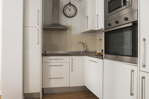 Cocina moderna blanca en ático Ab Be, apartamento Málaga con electrodomésticos de acero inoxidable y distribución compacta
