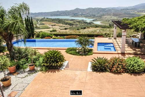 Luxury pool terrace with mountain lake views at Spanish hotel with palm trees and lounging areas