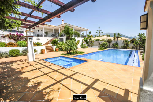 Luxury villa with swimming pools, terrace, and white Mediterranean architecture surrounded by tropical gardens