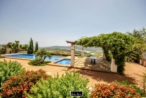 Luxury terrace with two pools, pergola, and vibrant red flowers overlooking scenic landscape in Spain