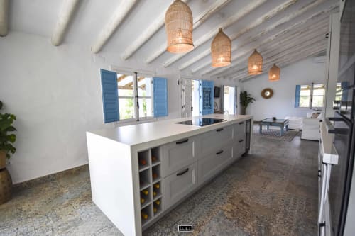 Modern open-plan kitchen with white island, woven pendant lights, and blue shutters at Escanda Building Solutions hotel in