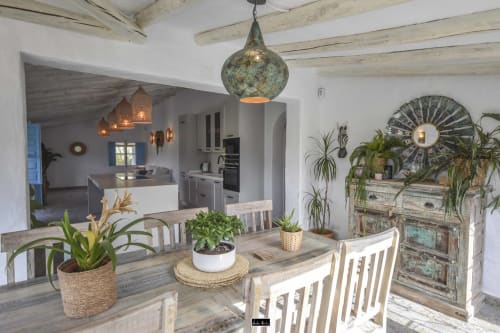 Bright dining area with wooden table, potted plants, and decorative pendant lamp in Spanish coastal hotel.
