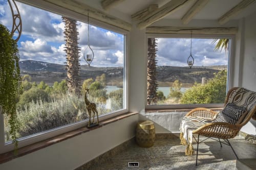 Sunlit room with panoramic lake and mountain views through large windows at Escanda hotel in Spain