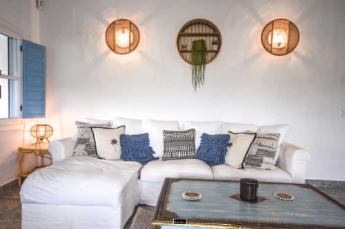 Modern coastal hotel room with white sectional sofa, blue accents, woven wall lights, and hanging plant at Escanda Building