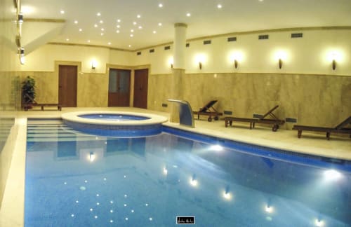 Indoor swimming pool with hot tub at Escanda Building Solutions hotel in Spain, featuring blue mosaic tiles and modern