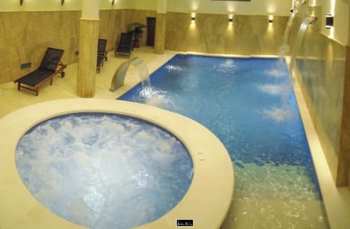 Indoor swimming pool area at Escanda hotel with hot tub, loungers, and yellow stone walls