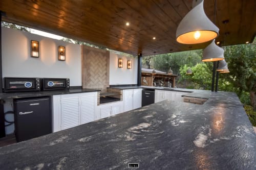 Luxury outdoor kitchen at Escanda Building Solutions hotel with white cabinetry, dark countertop, pendant lighting, and