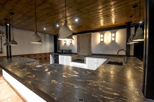 Modern hotel bar at Escanda Building Solutions with dark marble countertop, pendant lights, and white cabinetry