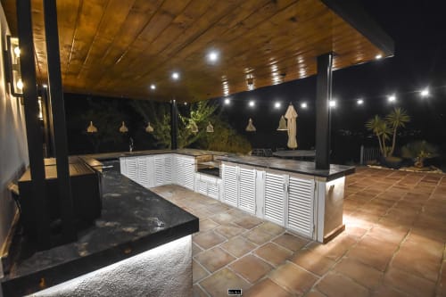 Modern outdoor kitchen terrace at Escanda Building Solutions hotel with white cabinetry, wooden ceiling, pendant lighting,