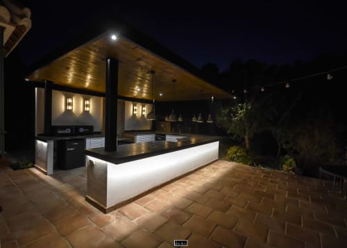 Modern outdoor kitchen pavilion at Escanda Building Solutions hotel in Spain, illuminated at night with black counters and