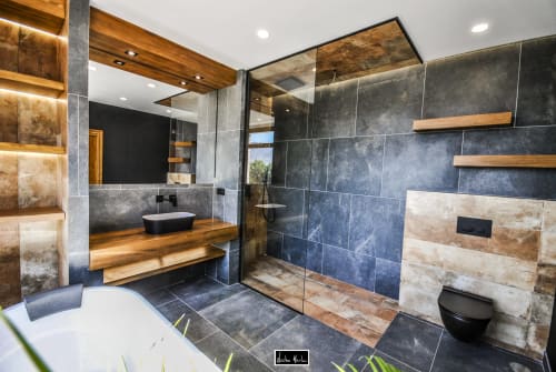 Modern luxury bathroom at Escanda Building Solutions hotel with slate tiles, wooden accents, and walk-in shower