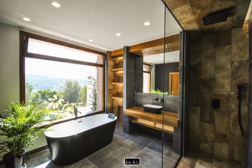 Luxury bathroom at Escanda Building Solutions hotel in Spain with black soaker tub, rainfall shower, dark tile finishes, and