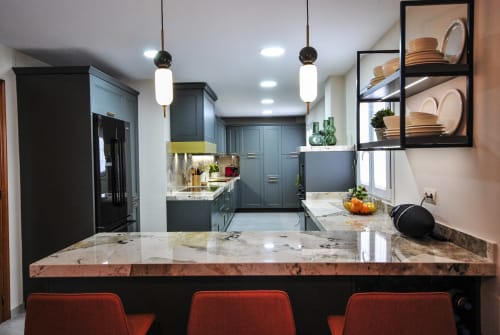 Modern kitchen at Escanda Building Solutions hotel with marble countertop, blue cabinetry, pendant lights, and red bar