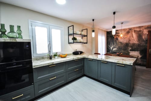 Modern kitchen at Escanda Building Solutions hotel with gray cabinetry, marble countertops, pendant lighting, and