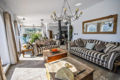 Bright open-plan living area with striped sofas, wooden tables, and large windows overlooking mountains at Escanda hotel,