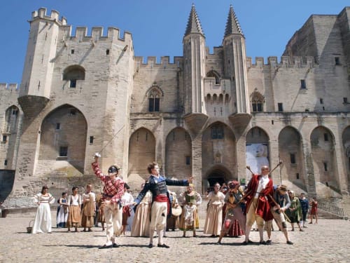 Medieval reenactment in courtyard of Le Prieuré Notre-Dame, Montfrin, with costumed performers and historic stone castle