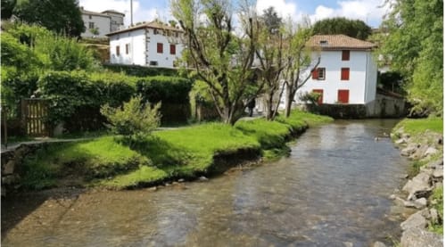 Vue paisible sur la rivière bordant le Moulin de Pascale dans le quartier Xerrenda à Espelette, un cadre bucolique et relaxant au Pays Basque.