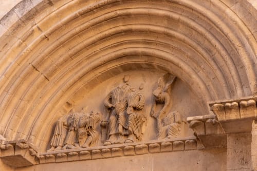 Ornate stone archway with carved religious figures at Le Prieuré Notre-Dame, Montfrin