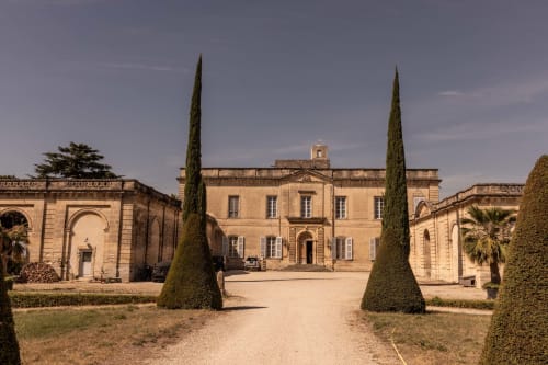 Le Prieuré Notre-Dame courtyard in Montfrin with cypress trees and stone French manor architecture
