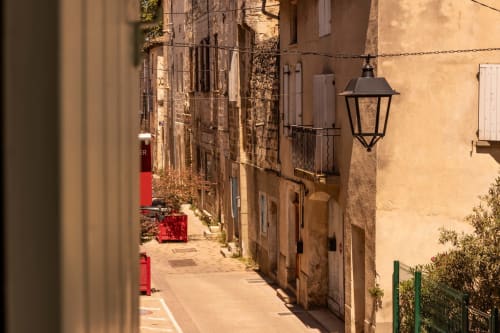 Charming narrow alley at Le Prieuré Notre-Dame in Montfrin, France, with terracotta buildings and vintage street lamp.
