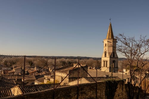 Golden church steeple overlooks Montfrin village rooftops at Le Prieuré Notre-Dame