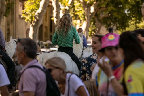 Child riding horse in tree-lined street at Le Prieuré Notre-Dame, Montfrin France