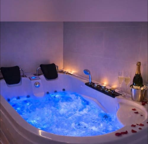 Lujoso baño spa con jacuzzi azul iluminado, champagne e iluminación ambiental en hotel Gestyp-AT, Mérida