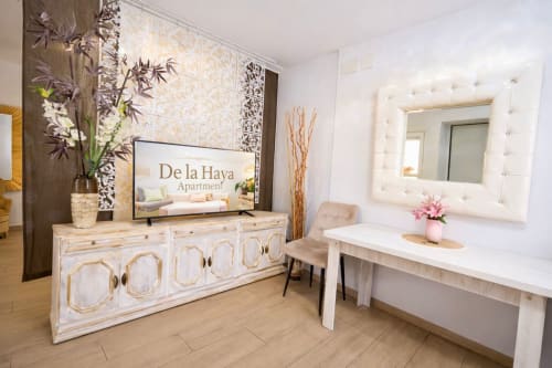 Elegante recepción de apartamentos modernos en Mérida con muebles blancos, paneles decorativos y entrada con vista a la ciudad en De la Haya