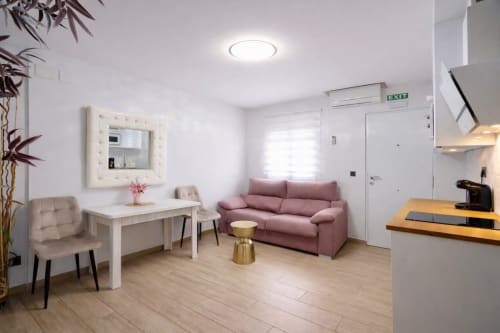 Apartamento moderno en Mérida con sofá rosa, escritorio de trabajo y zona de cocina - Gestyp-AT