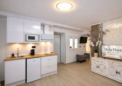 Cocina y sala de estar modernas en Gestyp-AT en Mérida con muebles blancos, encimeras de madera y diseño contemporáneo