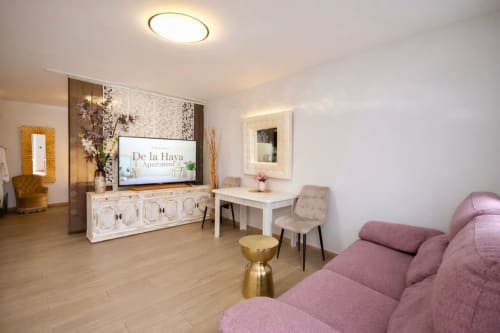 Moderno salón de apartamento en Mérida con sofá rosa, centro de entretenimiento con TV y vistas a la ciudad desde el hotel Gestyp-AT