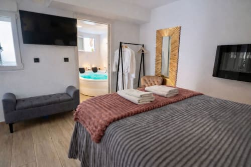 Recámara moderna en Mérida con camas matrimoniales, acceso a jacuzzi, sofá gris y vistas de la ciudad