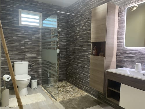 Salle de bain moderne tout confort avec WC, douche à l'italienne, meuble vasque rangement et porte-serviettes.