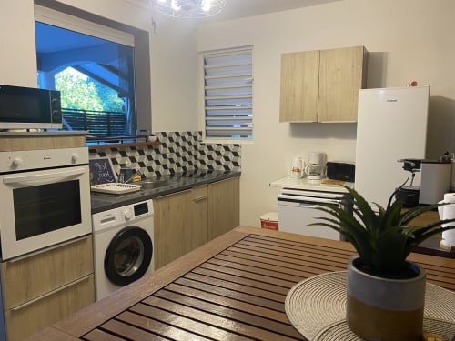 Grande cuisine entièrement équipée avec four encastrable, micro-ondes, plaque à induction, lave-vaisselle, réfrigérateur, congélateur, lave-linge, cafetière, grille-pain, bouilloire, table mange debout et rangements.