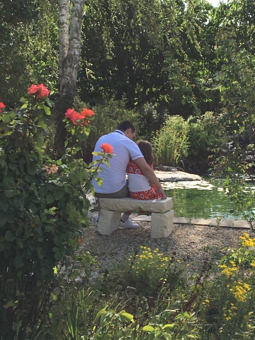 Couple se relaxant sur un banc de jardin entouré de roses en fleur à La Chabanaise, gîte du Marais Poitevin