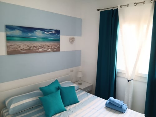 Accogliente camera da letto dell'appartamento di Varenna con accenti turchesi, arte murale a tema marino e comfort moderni