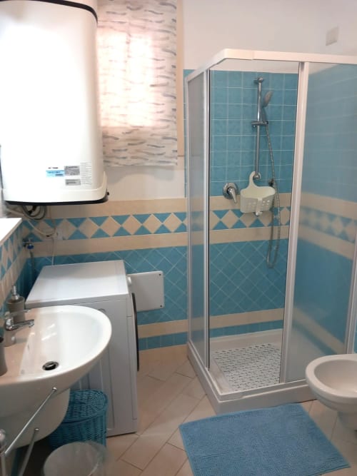 Bagno moderno a Varenna by Foot con doccia in piastrelle turchesi, lavandino bianco, WC e scaldabagno