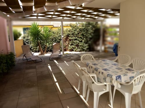 Patio coperto con tavolo da pranzo e sedie presso l'appartamento Varenna, con vista montagna e vegetazione lussureggiante
