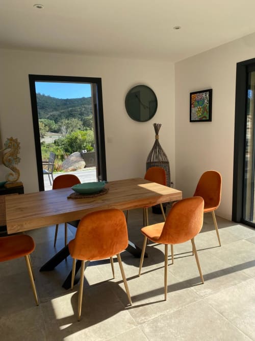 Modern dining room in Villa Ô Bord de Mer, Favone, with wooden table, orange chairs, and mountain views, managed by Corsu di Core