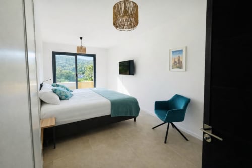 Modern bedroom in Villa Lagon Bleu at  Favone, with pool view, teal accents, and contemporary furnishings, managed by Corsu di Core conciergerie