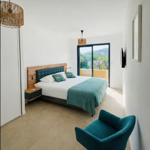 Modern bedroom in Lagon Bleu villa with mountain views, teal accents, and wooden furnishings, managed by Corsu di Core conciergerie