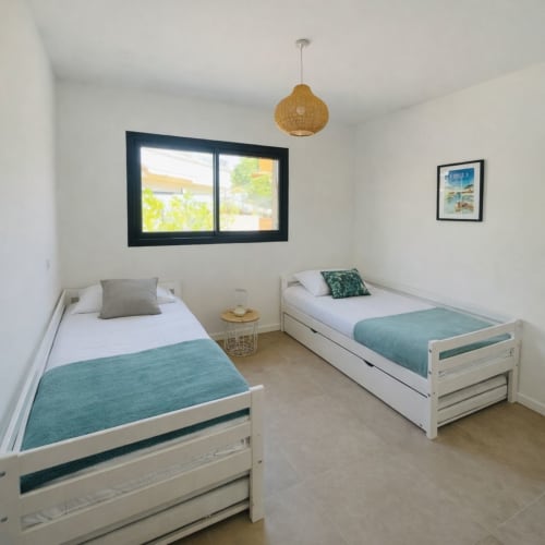 Twin bedroom in Lagon Bleu villa with white beds, turquoise throws, and pool view window in Favone, managed by Corsu di Core conciergerie