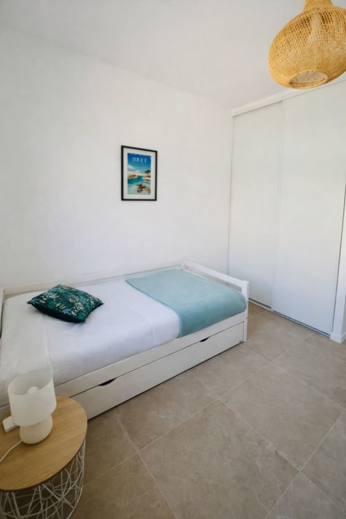 Modern bedroom in Villa Lagon Bleu at  Favone, with white bed, turquoise runner, woven pendant lamp, managed by Corsu di Core