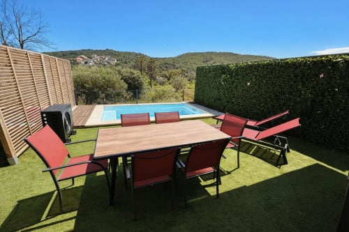 Villa Corail garden with pool, dining table, red lounge chairs, and mountain views in Favone, Corsica, managed Corsu di Core