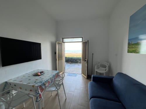 Luminoso appartamento fronte mare a Marina di Strongoli con vista sul mare, zona pranzo, divano, TV a schermo piatto e accesso diretto alla spiaggia