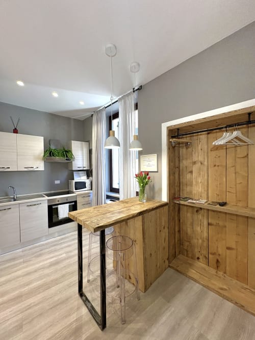Moderna cucina di appartamento a Verona con isola in legno, cabinetry bianca, lampade a sospensione e armadio in legno.