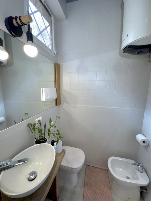 Moderno bagno nell'appartamento Cantore 20 presso Le Arche, Verona, con piastrelle bianche, lavabo tondo, WC, bidet e luce naturale