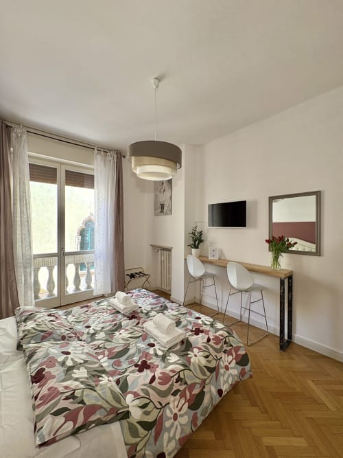 Camera moderna all'Il Tenore B&B di Verona con biancheria floreale, scrivania, TV schermo piatto e vista città dal balcone