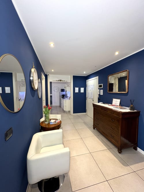 Moderna hall di Le Arche Verona con pareti blu navy, soffitto bianco, arredamento elegante e reception